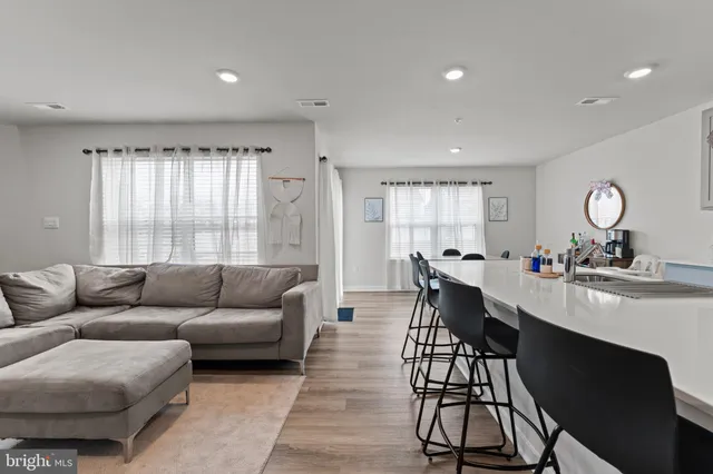 a living room with furniture a flat screen tv and a refrigerator