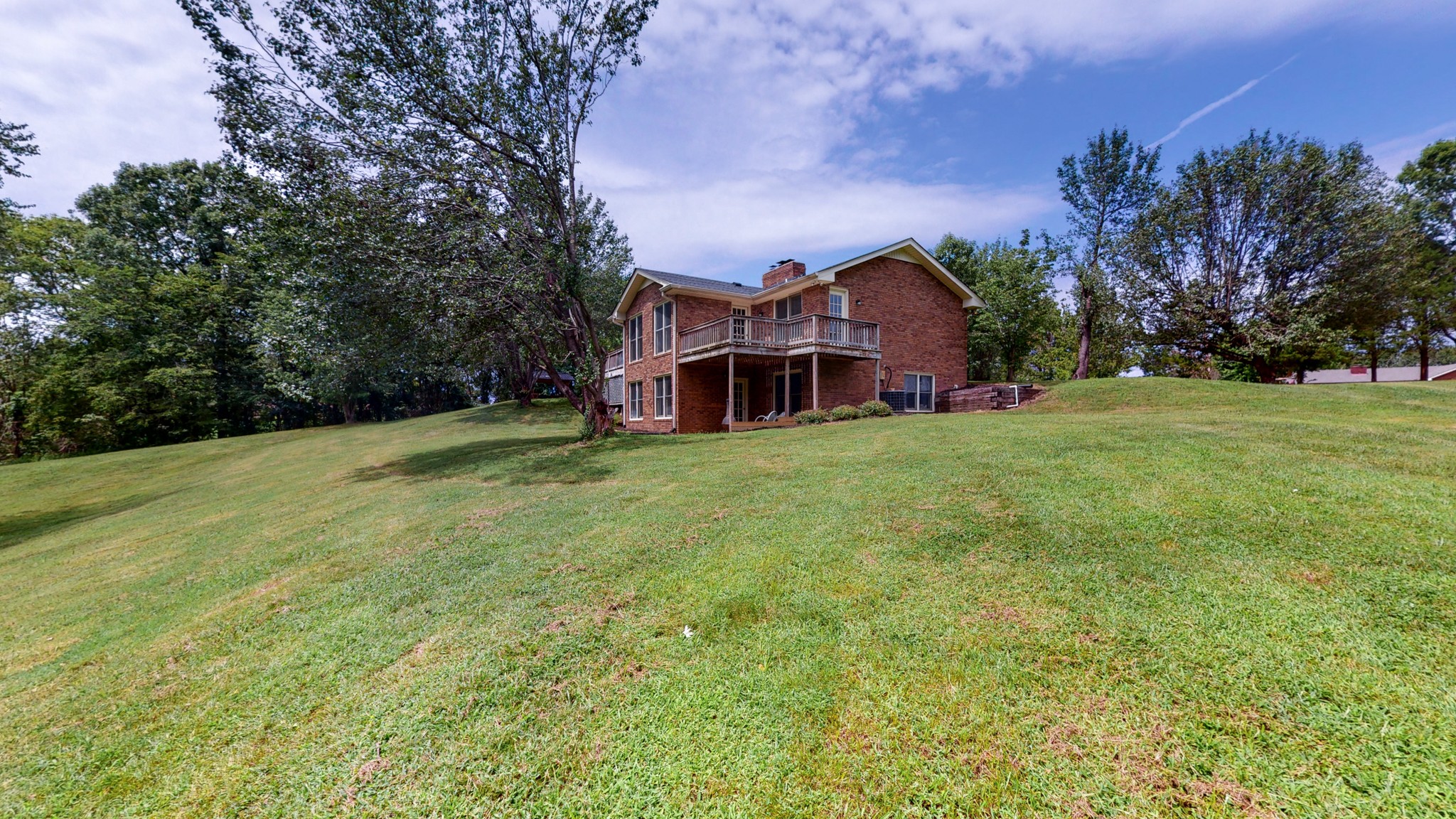 a view of a house with a big yard and large trees