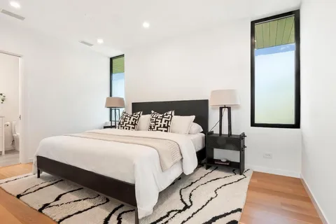 a bedroom with a bed a mirror and wooden floor