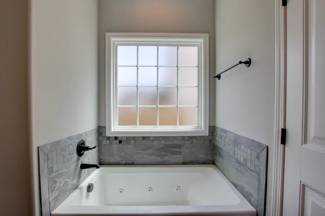 an empty room with windows a fireplace a ceiling fan and wooden floor