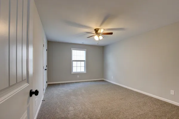 an empty room with wooden floor fireplace fan and windows