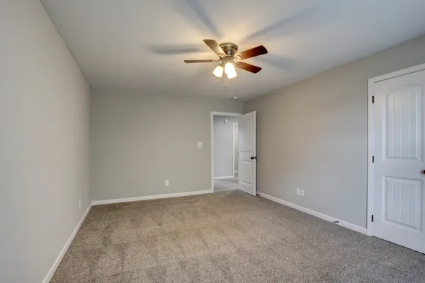 a view of an empty room with a fan and a window