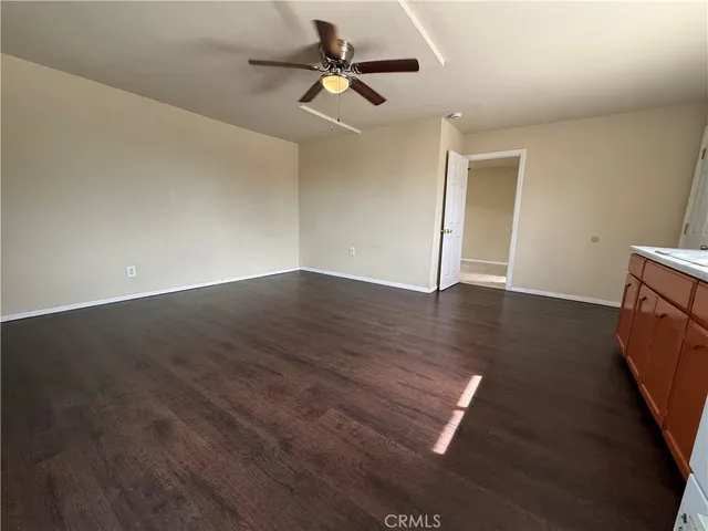 an empty room with wooden floor cabinet and windows