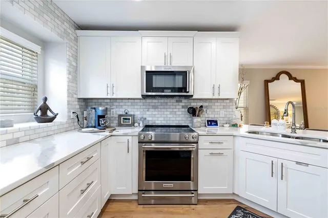 a kitchen with cabinets stainless steel appliances a sink and a window