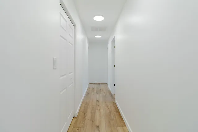 a view of empty room with wooden floor and window