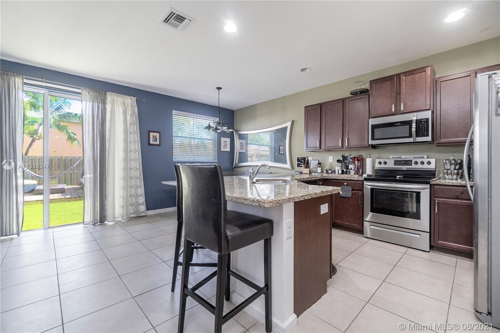 12119 Southwest 253rd Street Homestead, FL 33032 - Photo 14 of 46 a kitchen with stainless steel appliances granite countertop a stove a sink a microwave and a refrigerator