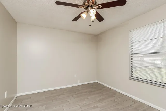 an empty room with a window and a fan