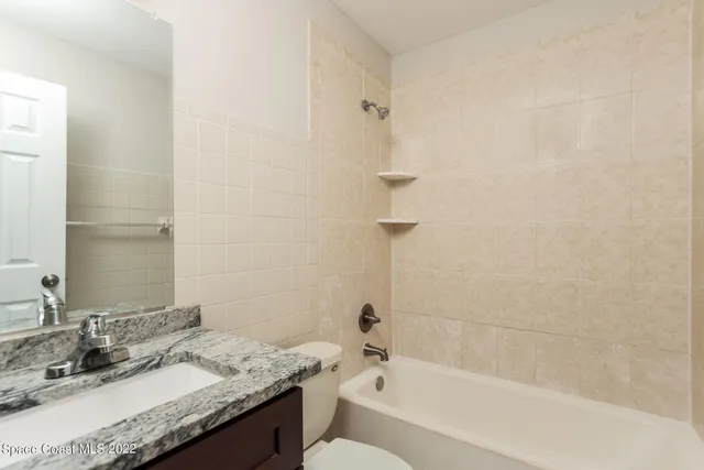 a bathroom with a granite countertop sink a mirror and a bathtub