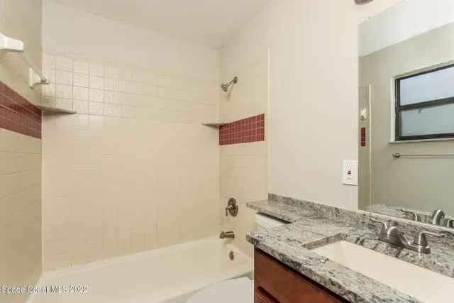 a bathroom with a granite countertop bathtub sink vanity and mirror