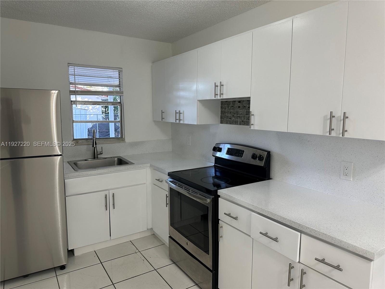 1920 Northwest 4th Street, Unit B Miami, FL 33125 - Photo 6 of 14 a kitchen with white cabinets sink and white appliances