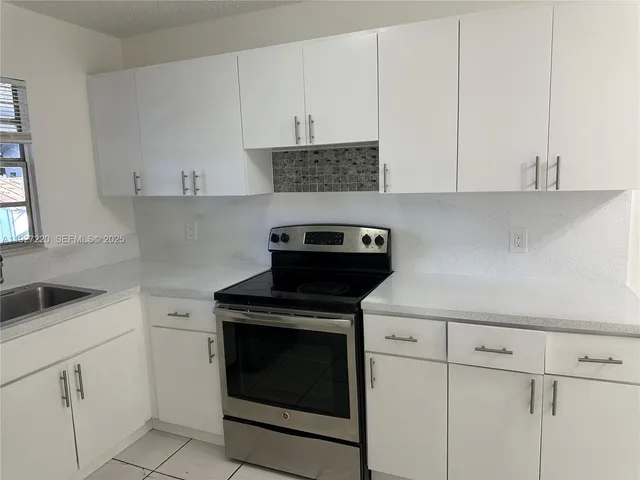 a kitchen with white cabinets and black appliances