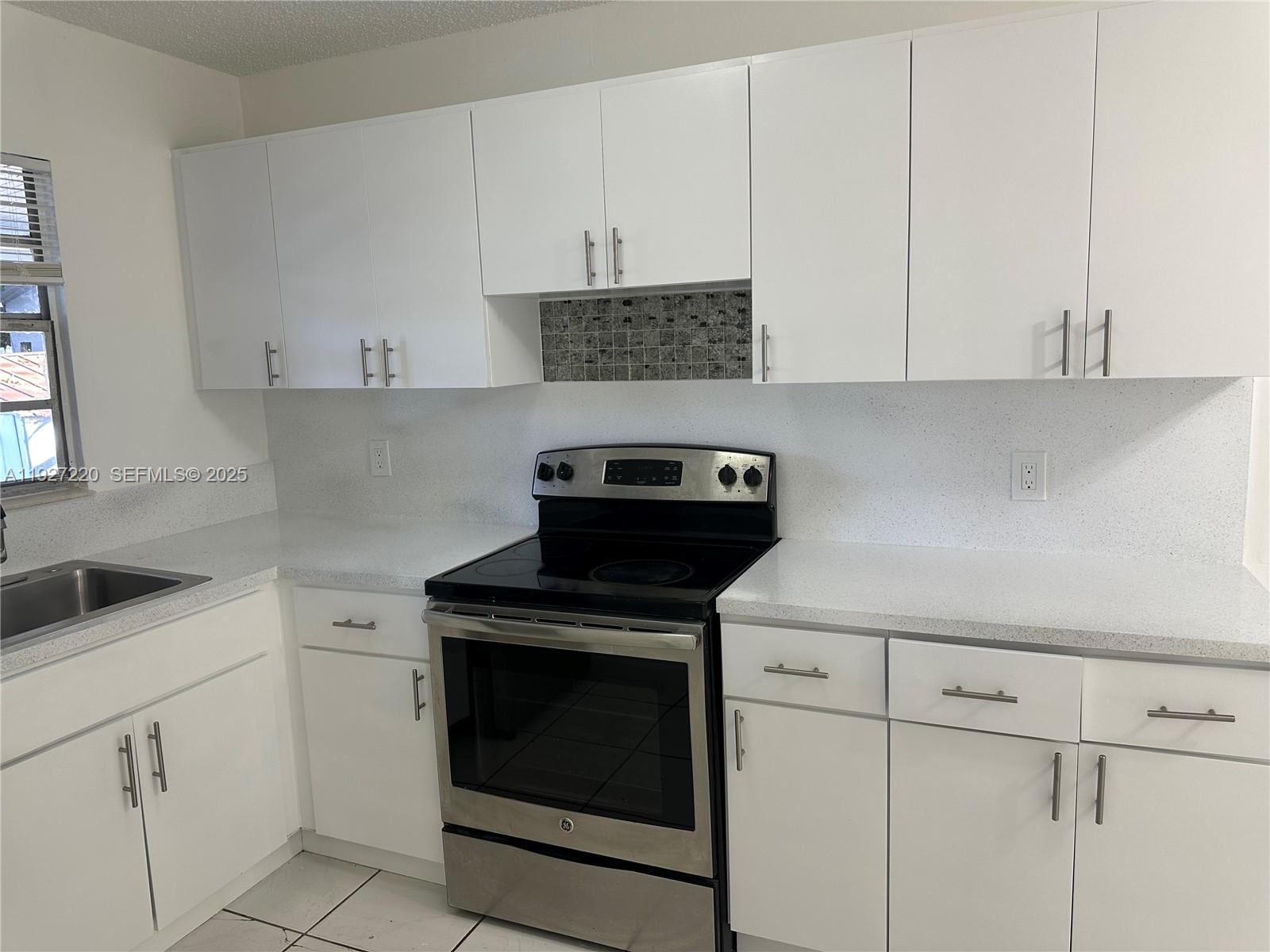 1920 Northwest 4th Street, Unit B Miami, FL 33125 - Photo 7 of 14 a kitchen with white cabinets and black appliances