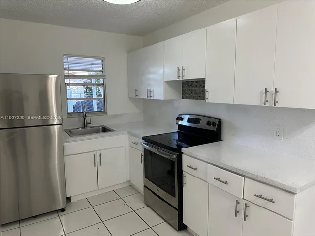 a kitchen with white cabinets and appliances