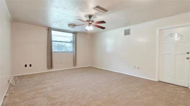 an empty room with chandelier fan and windows
