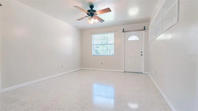 an empty room with windows and fan