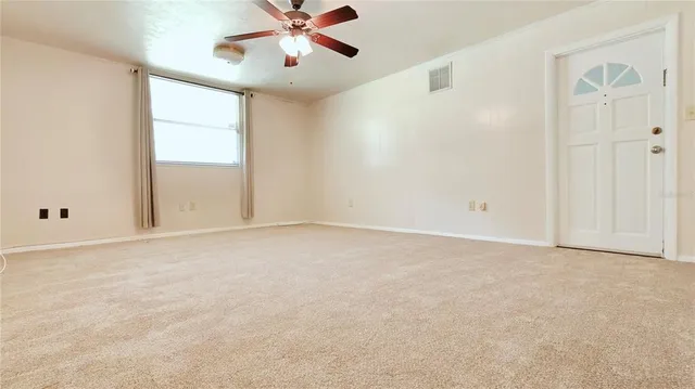 an empty room with windows and fan