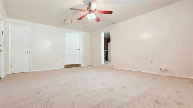 an empty room with chandelier fan and closet area