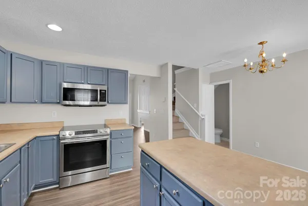 a kitchen with granite countertop a stove top oven a sink dishwasher and a refrigerator with wooden floor