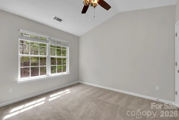 an empty room with ceiling fan and window