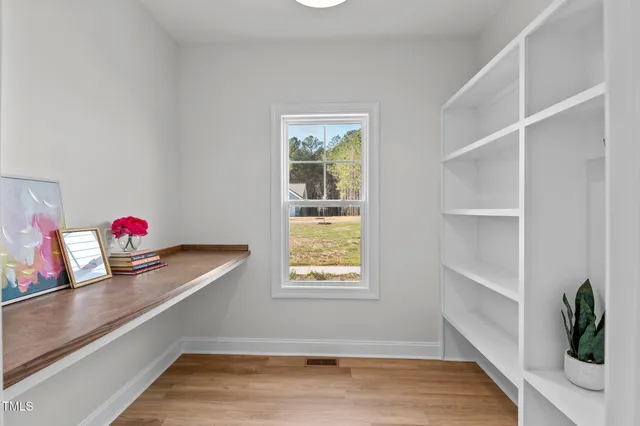 an empty room with wooden floor a ceiling fan and windows
