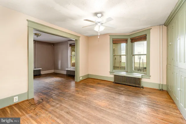 a view of an empty room with wooden floor and a window