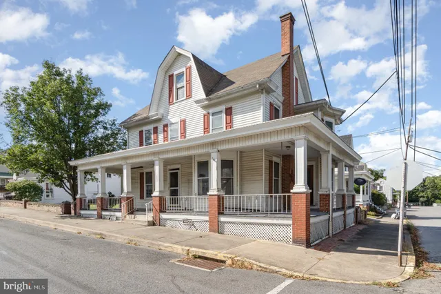 a front view of a house with a garden and trees
