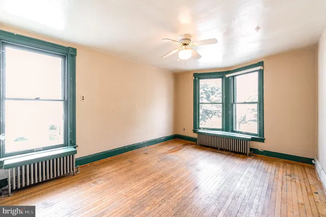 an empty room with wooden floor fan and windows