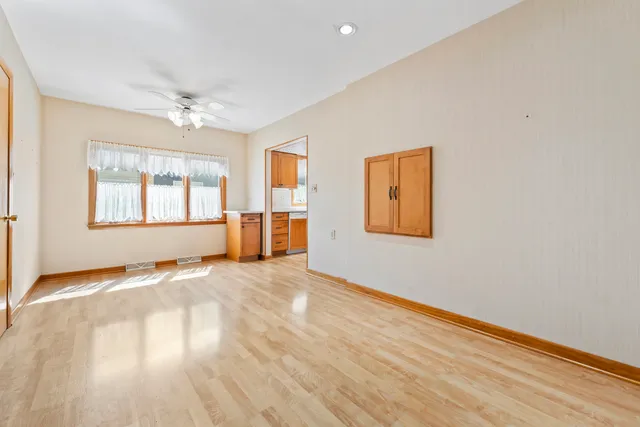 a view of an empty room with a window and wooden floor