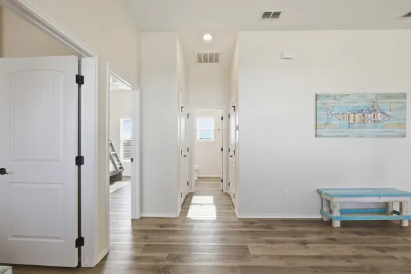 a view of an empty room with wooden floor and a bathroom