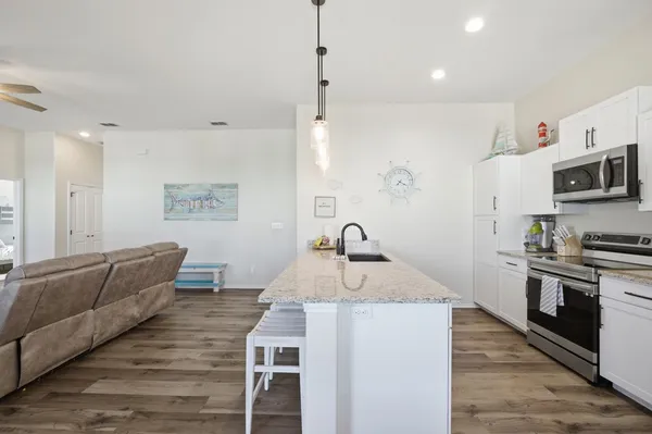 a kitchen with stainless steel appliances granite countertop a sink dishwasher a stove and a refrigerator with wooden floor