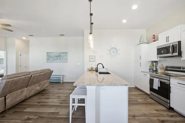 a kitchen with stainless steel appliances granite countertop a sink dishwasher a stove and a refrigerator with wooden floor