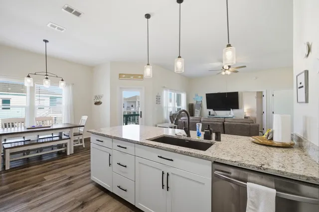 a kitchen with stainless steel appliances kitchen island granite countertop a sink a stove and a wooden floor