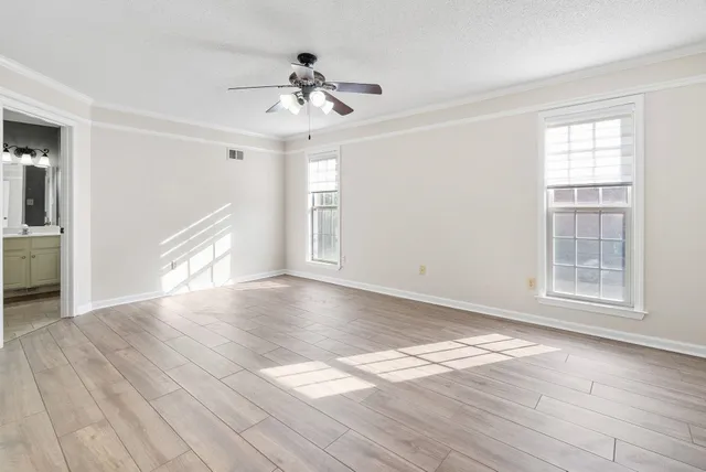 a view of empty room with wooden floor and fan
