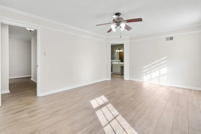 a view of empty room with wooden floor and fan