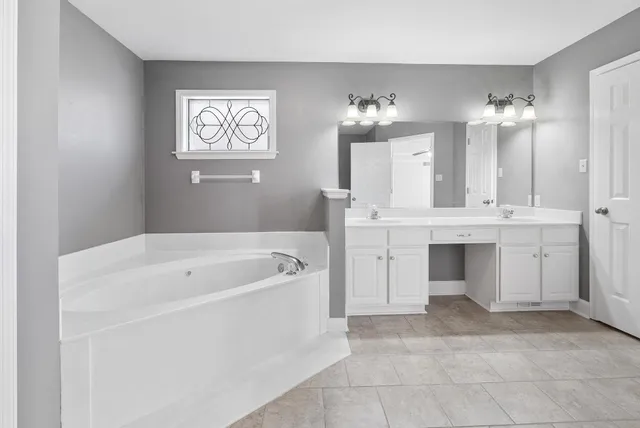 a spacious bathroom with a tub sink a mirror and vanity