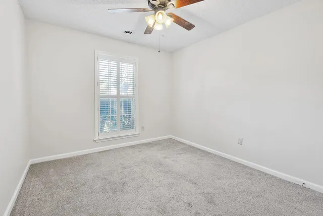 an empty room with a window and a fan