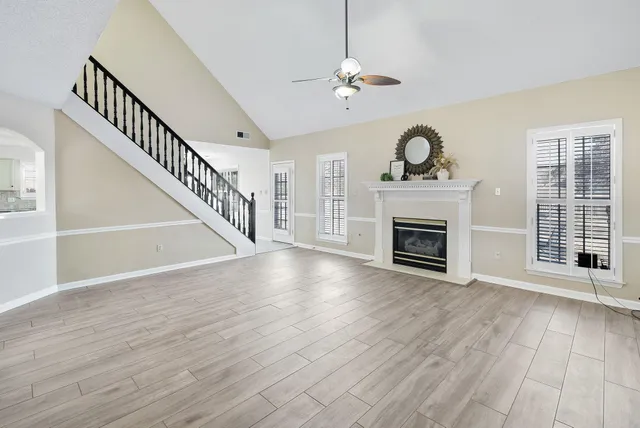 a view of an empty room with wooden floor fireplace and a window