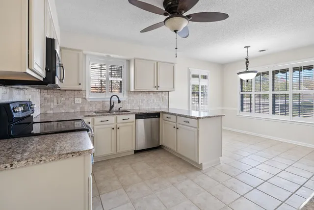 a kitchen with granite countertop a sink stainless steel appliances and cabinets