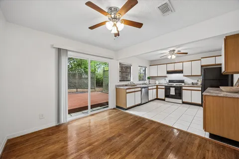 a large kitchen with stainless steel appliances granite countertop a stove top oven a sink dishwasher a dining table and chairs with wooden floor