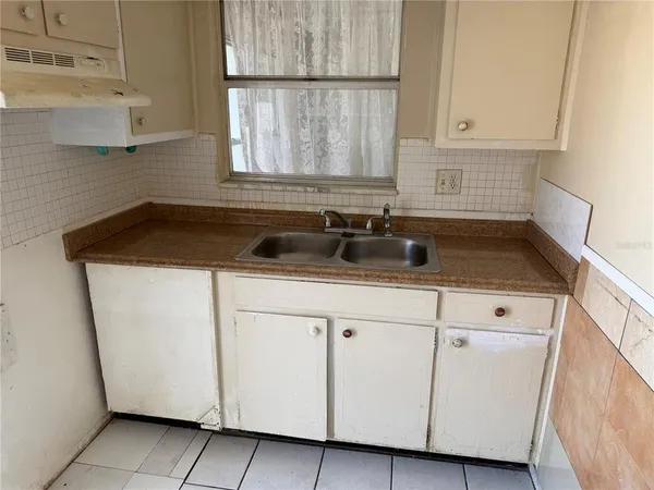 a kitchen with white cabinets and sink