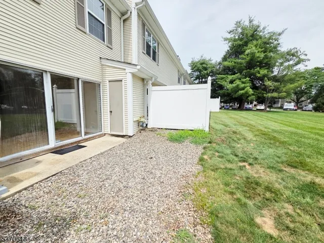 a view of a white house with a yard and large tree