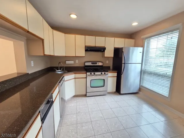 a kitchen with stainless steel appliances granite countertop a stove a sink and a refrigerator