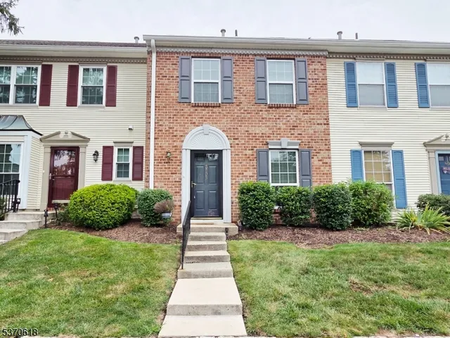 a view of brick house with a yard and plants