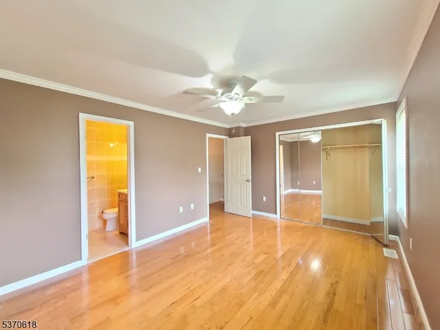 an empty room with wooden floor and a ceiling fan