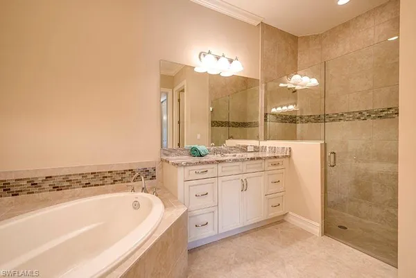 a bathroom with a granite countertop sink a large mirror and a bathtub