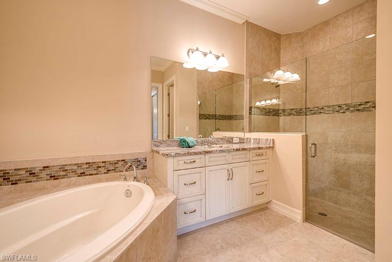 6564 Roma Way Naples, FL 34113 - Photo 14 of 22 a bathroom with a granite countertop sink a large mirror and a bathtub