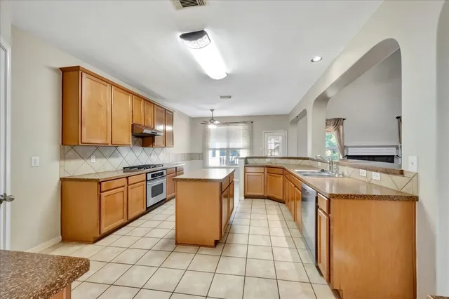 a large kitchen with stainless steel appliances granite countertop a stove a sink dishwasher and a refrigerator