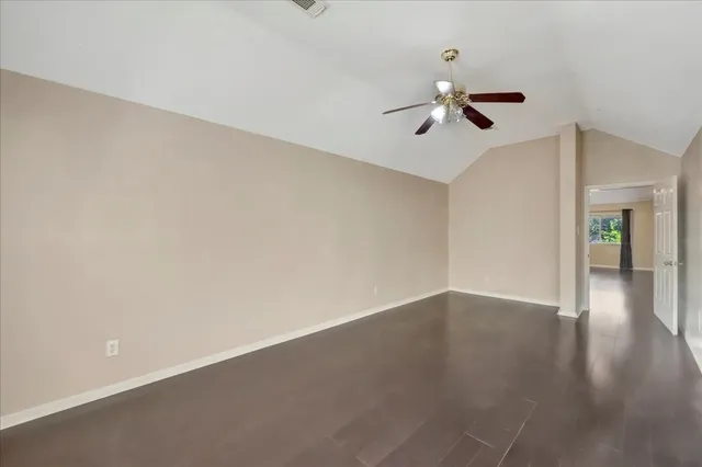 an empty room with a ceiling fan and wooden floor