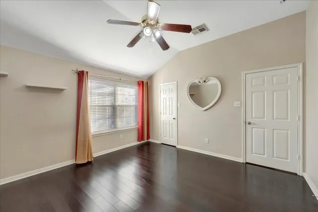 an empty room with wooden floor fan and windows