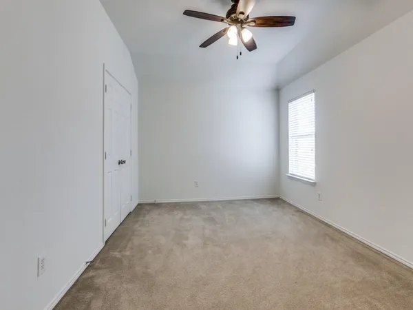 an empty room with windows and fan